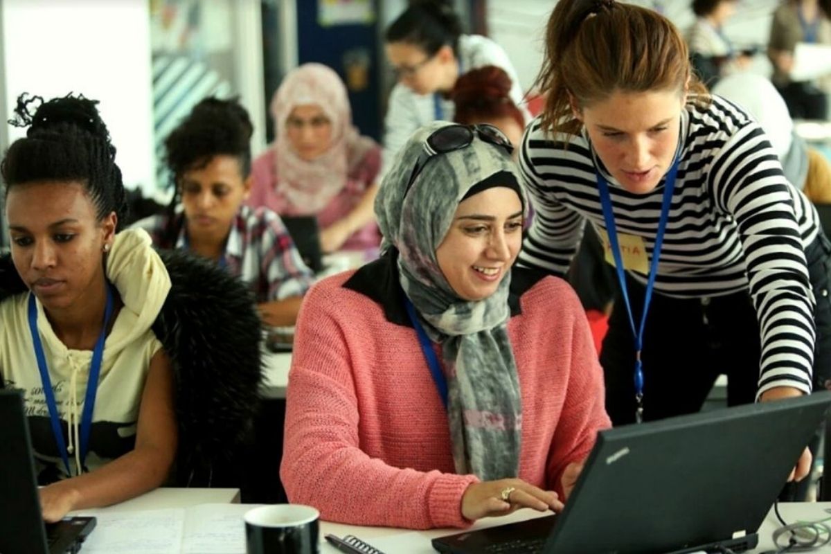 Auf dem Foto sind mehrere Personen zu sehen, die zusammen auf einen Laptop schauen.