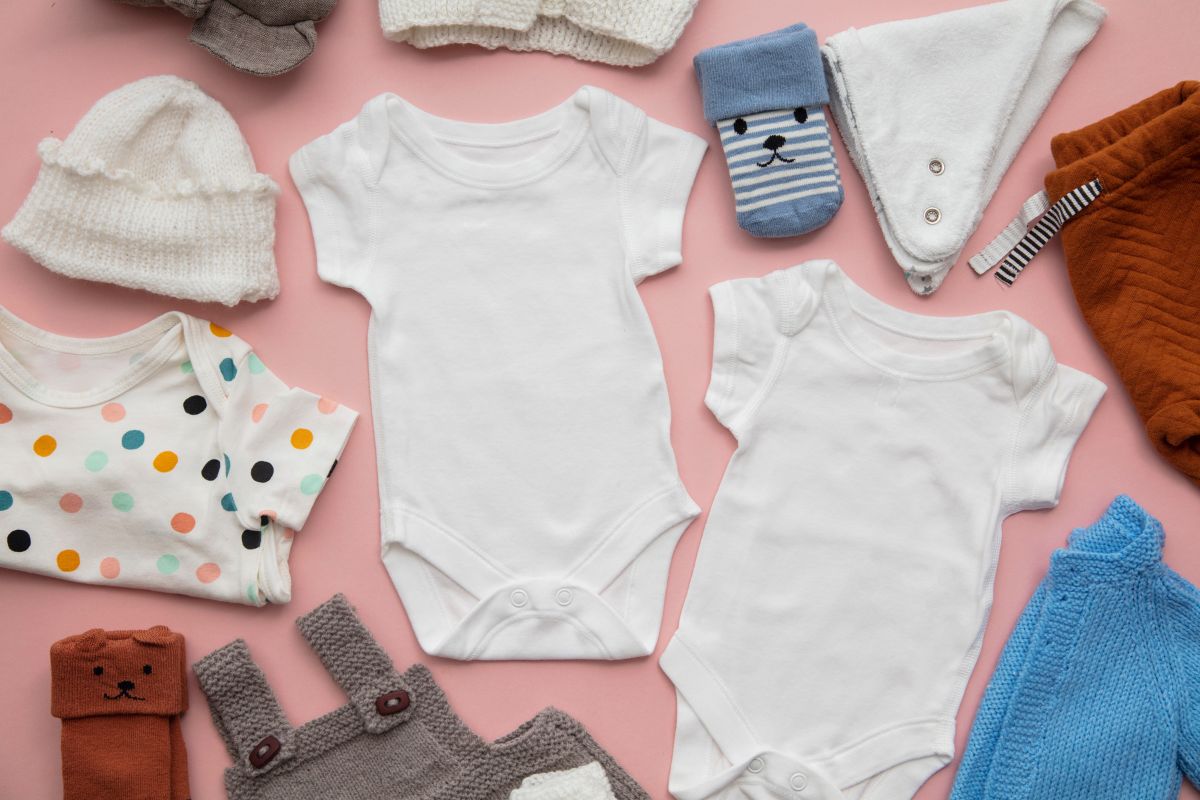 Baby clothes against a pink background.