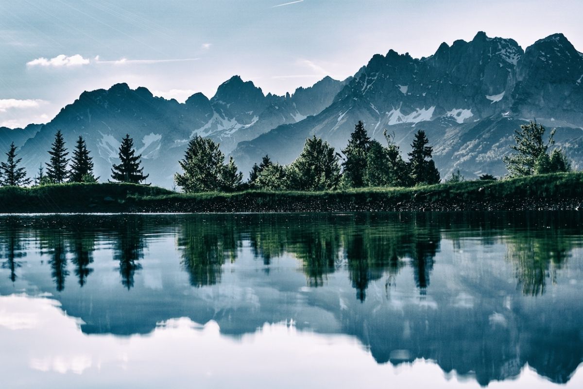 Auf dem Foto sind Bäume und Berge zu sehen, die sich in einem See spiegeln.