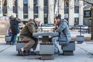 Auf dem Bild sind zwei Personen zu sehen, die draußen Schach spielen.