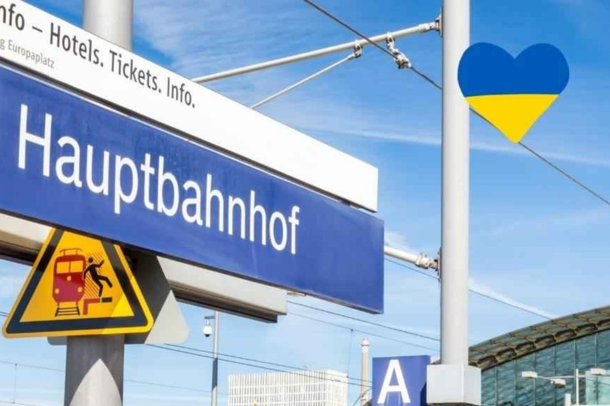 Das Bild zeigt den berliner Hauptbahnhof gekennzeichnet durch ein Schild, auf dem Hauptbahnhof steht. Im oberen rechten Bildrand ist ein Herz zu erkennen in den Farben der ukrainischen Nationalflagge.