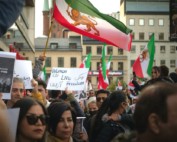 Auf dem Foto sind Menschen auf einer Demonstration für Menschenrechten im Iran zu sehen. Auf den Schildern stehen Sätze wie "Women Life Freedom".