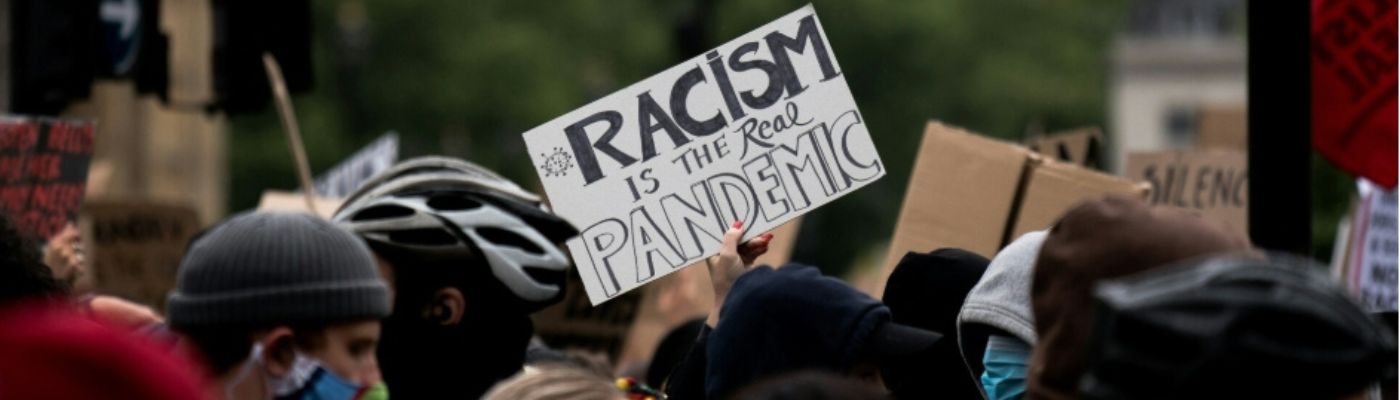 Demo gegen Rassismus und Diskriminierung mit Schild "Racism is the real pandemic."