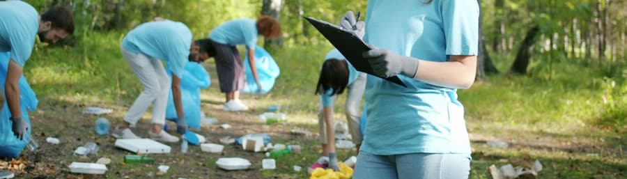 Junge Menschen helfen beim Sammeln von Müll im Wald.