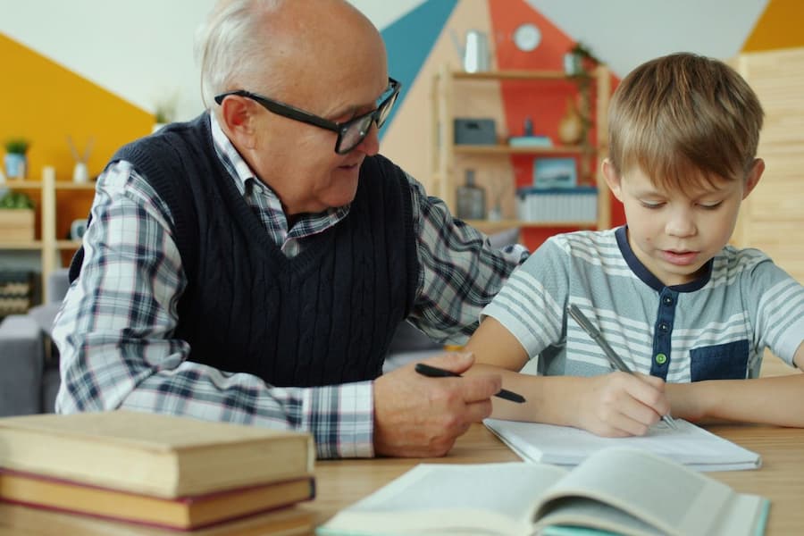 Ein älterer Mann hilft einem Kind bei den Hausaufgaben